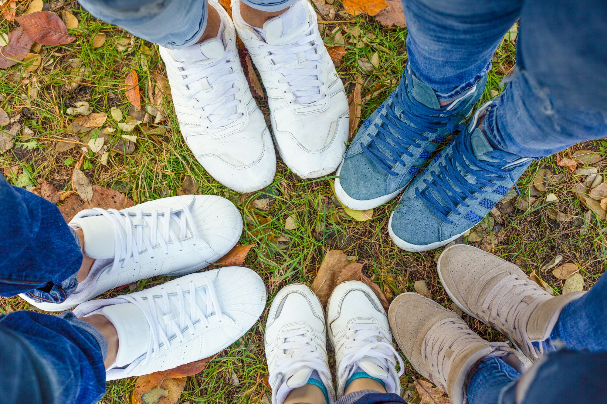 Legs of people in sneakers. The family walks in a circle. Team building team runs outdoors in autumn